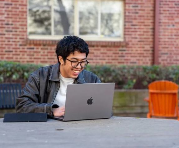 student with laptop outside pac campus
